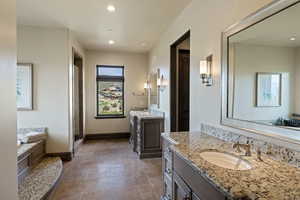 Full bathroom with two vanities, a garden tub, stone tile flooring, recessed lighting, and a stall shower