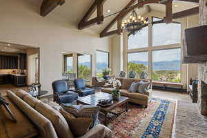 Living room with high vaulted ceiling, a stone fireplace, beam ceiling, recessed lighting, and a mountain view