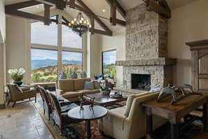Living area featuring a fireplace, high vaulted ceiling, beamed ceiling, a mountain view, and stone tile floors