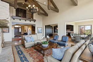Tiled living room with high vaulted ceiling, beam ceiling, a chandelier, arched walkways, and recessed lighting
