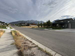 View of asphalt road with sidewalks, a mountain view, and curbs