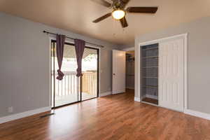Unfurnished bedroom featuring wood finished floors, access to outside, and ceiling fan