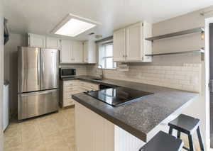 Kitchen featuring open shelves, appliances with stainless steel finishes, white cabinetry, and backsplash