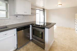 Kitchen featuring white cabinets, appliances with stainless steel finishes, light tile patterned flooring, tasteful backsplash, and a peninsula