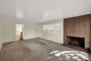 Unfurnished living room with a fireplace and carpet flooring
