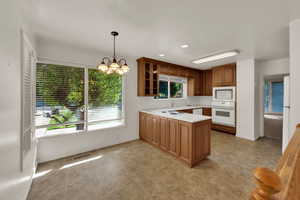 Kitchen with a chandelier, white appliances, light countertops, recessed lighting, and hanging light fixtures