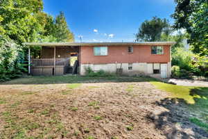 Rear view of house featuring brick siding, stairway, and a lawn