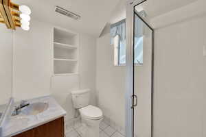 Full bath with light tile patterned floors, vanity, a shower stall, built in features, and lofted ceiling
