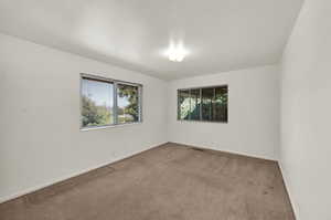 Empty room featuring healthy amount of natural light and carpet
