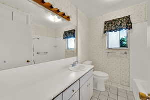 Full bath with healthy amount of natural light, light tile patterned flooring, wallpapered walls, vanity, and shower / tub combination