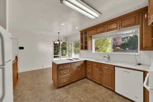 Kitchen with brown cabinetry, white appliances, glass insert cabinets, decorative backsplash, and recessed lighting