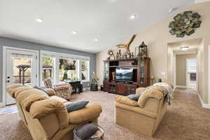 Carpeted living room featuring vaulted ceiling, recessed lighting, and a textured ceiling