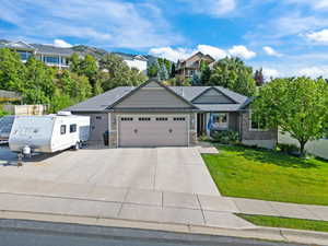 Craftsman-style house with stone siding, concrete driveway, a garage, and a front yard