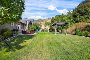 View of green lawn featuring a mountain view, a patio area, a playground, and a pergola