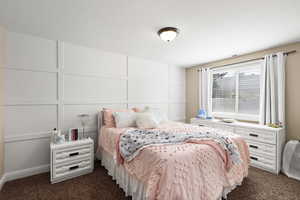 Bedroom with dark colored carpet and a decorative wall