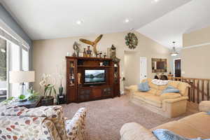 Carpeted living area featuring vaulted ceiling and baseboards