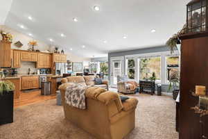 Living room featuring vaulted ceiling, light colored carpet, recessed lighting, a chandelier, and a textured ceiling