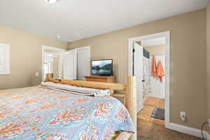 Carpeted bedroom featuring baseboards and ensuite bathroom