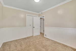 Carpeted empty room with crown molding and wainscoting