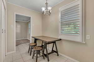 Dining area featuring light tile patterned floors, crown molding, and a chandelier