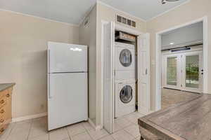 Washroom with light tile patterned floors and estacked washer and dryer