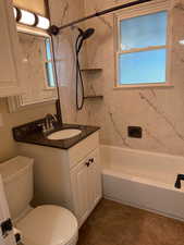 Bathroom featuring shower / bathtub combination, vanity, and plenty of natural light
