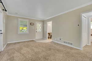 Entryway with crown molding and light carpet