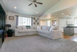 Living area featuring vaulted ceiling, recessed lighting, light carpet, a chandelier, and a ceiling fan