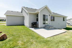 Back of property with a patio, roof with shingles, and a yard