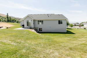 Rear view of property featuring a lawn and a patio area