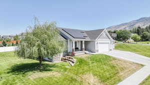 Craftsman-style house featuring solar panels, stone siding, driveway, covered porch, and a shingled roof