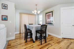 Dining space with light wood-style floors and a chandelier