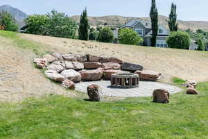 View of grassy yard featuring a patio, a mountain view, and an outdoor fire pit