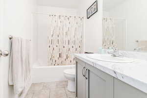 Full bath featuring shower / bathtub combination with curtain, vanity, and light tile patterned flooring