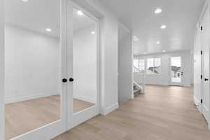 Corridor featuring recessed lighting, light wood finished floors, stairs, and french doors