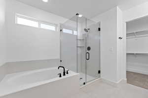 Full bath featuring a walk in closet, a bath, a stall shower, light tile patterned floors, and recessed lighting