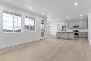 Kitchen with stainless steel appliances, gray cabinets, light countertops, recessed lighting, and decorative backsplash