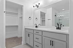 Full bathroom with a walk in closet, double vanity, a stall shower, light carpet, and light tile patterned flooring