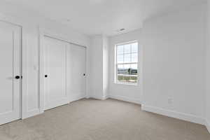 Unfurnished bedroom featuring light carpet and a closet