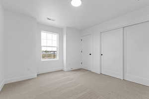 Unfurnished bedroom with light colored carpet and a closet