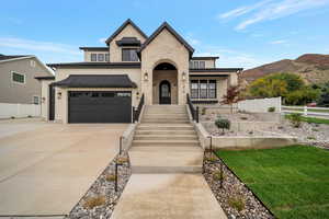 French country style house featuring stone siding, stucco siding, driveway, and a standing seam roof
