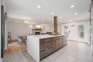 Kitchen with ornamental molding, a tile fireplace, recessed lighting, light countertops, and a kitchen island