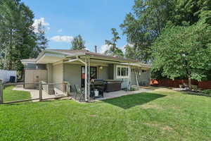 Rear view of property with a patio area, a fenced backyard, brick siding, and a hot tub