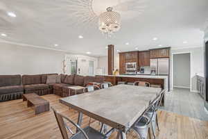 Dining space with recessed lighting, crown molding, light wood-type flooring, and a chandelier