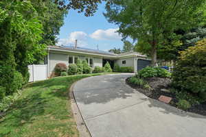 Ranch-style house featuring a garage, concrete driveway, brick siding, and solar panels