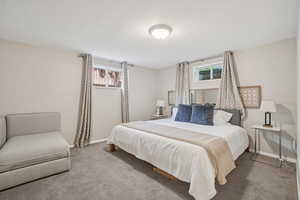 Carpeted bedroom featuring a textured ceiling and baseboards