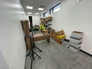 Home office with a drop ceiling and unfinished concrete flooring