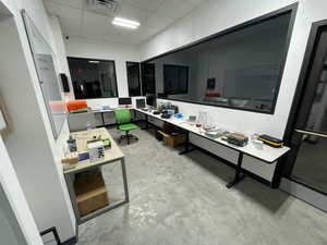 Home office with a paneled ceiling and unfinished concrete flooring