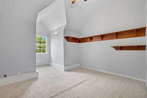 Bonus room with light colored carpet, lofted ceiling, a ceiling fan, and a baseboard radiator