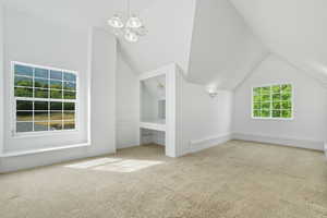 Additional living space with lofted ceiling, light colored carpet, a chandelier, and a baseboard radiator